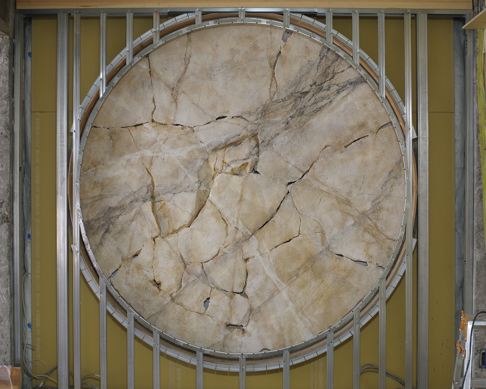 モルタル造形で制作した、クラックの入った円形の白い岩壁の写真